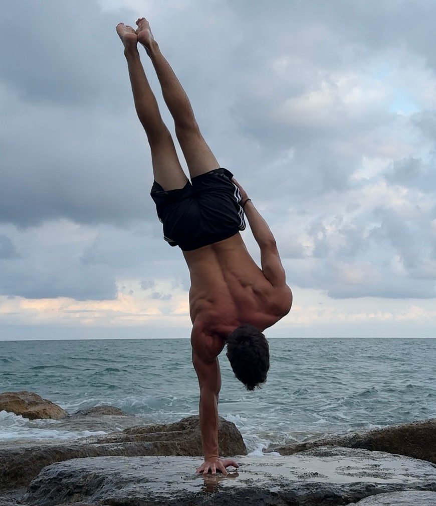 Iván Bustamante practicando pino a un brazo junto al mar